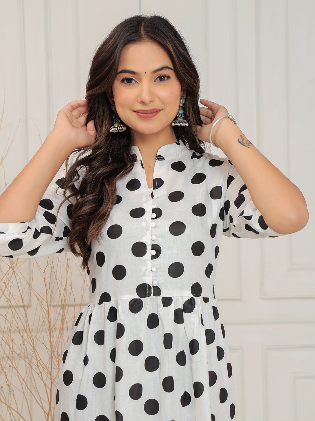 Woman wearing a white dress with black polka dots against a light background