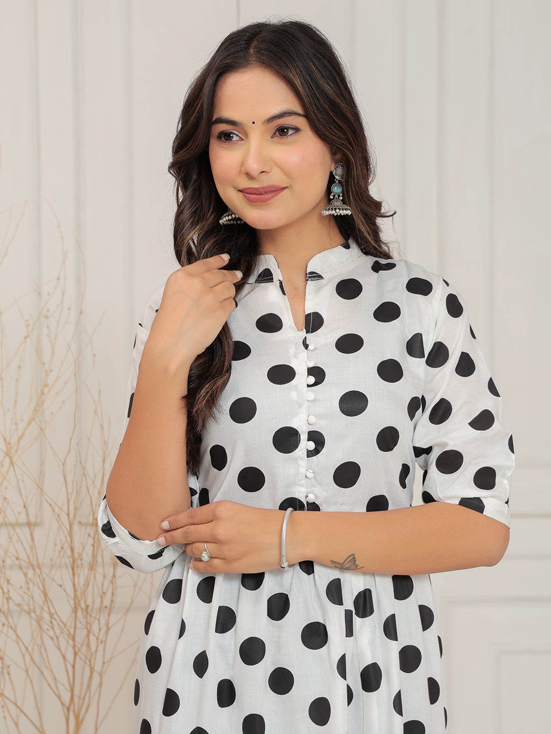 Woman wearing a white dress with black polka dots against a light background