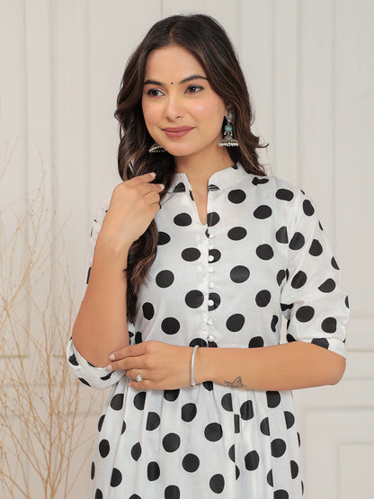 Woman wearing a white dress with black polka dots against a light background
