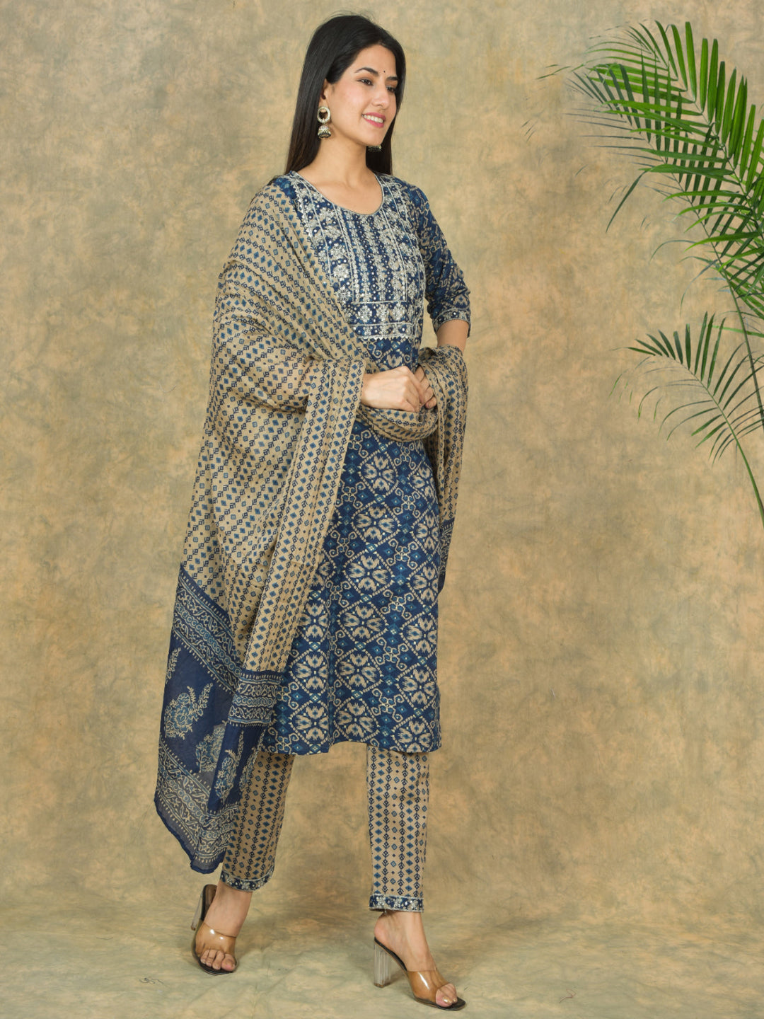 Woman wearing a traditional outfit with a patterned shawl against a beige background