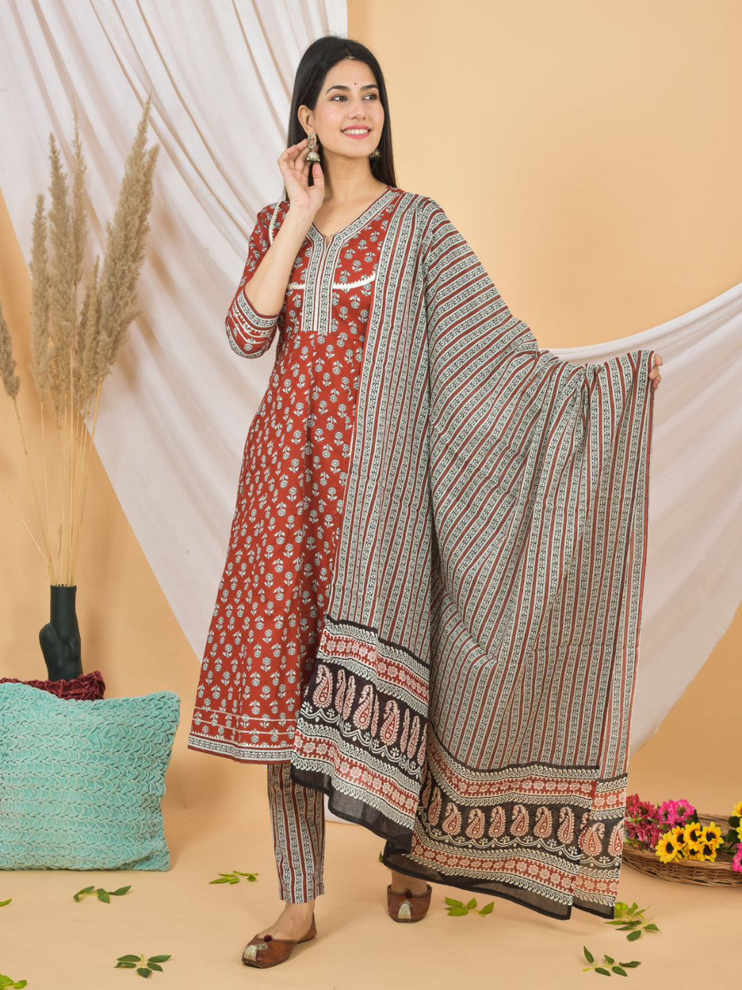 Woman wearing a traditional outfit with a red and white top and patterned pants on a beige background. > Mitrika