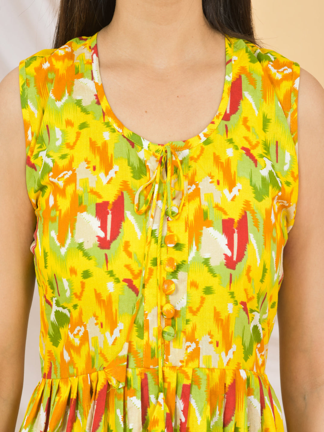 Yellow sleeveless top with colorful floral pattern on a beige background