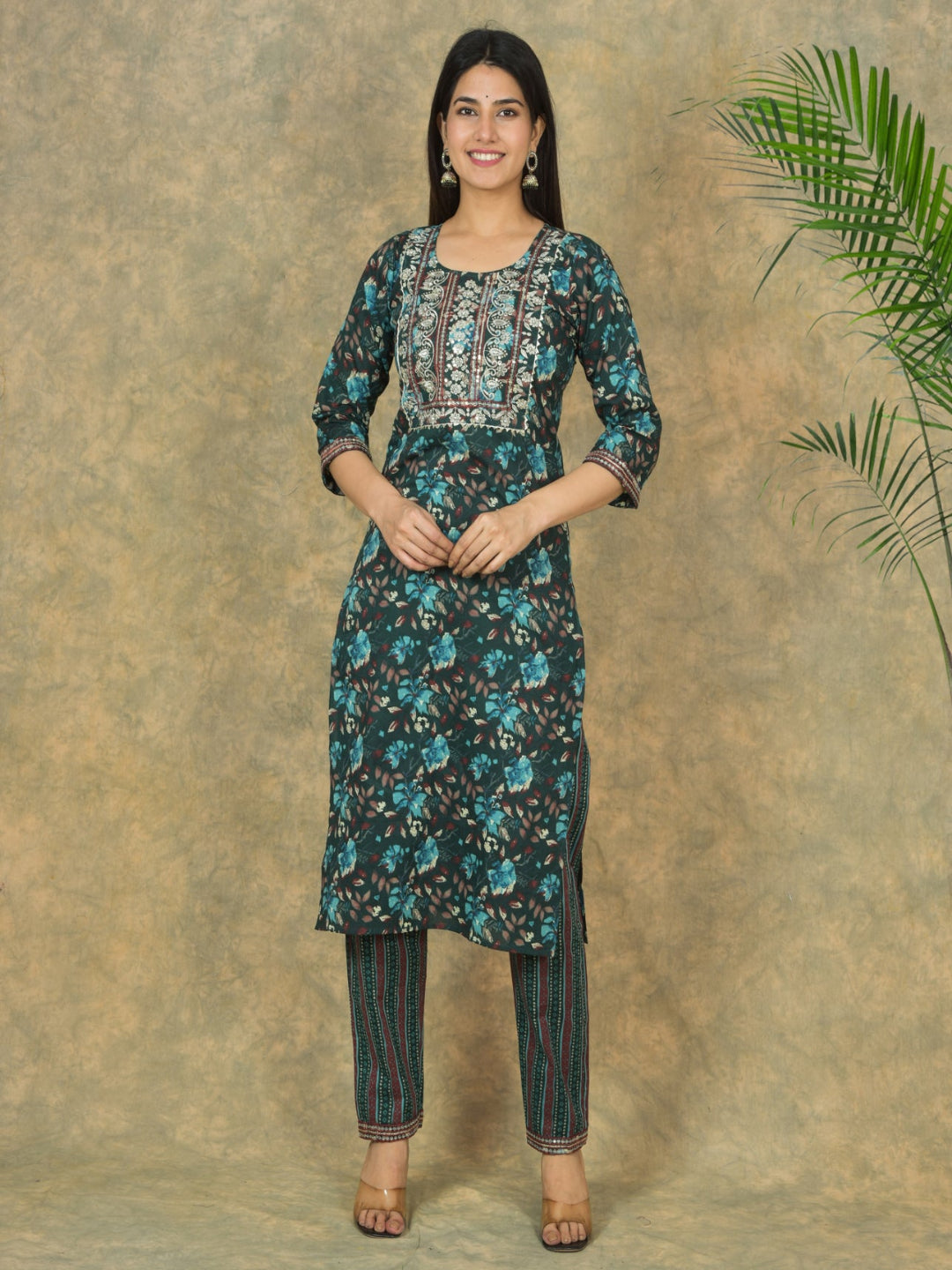 Woman wearing a floral kurta with pants against a textured brown background