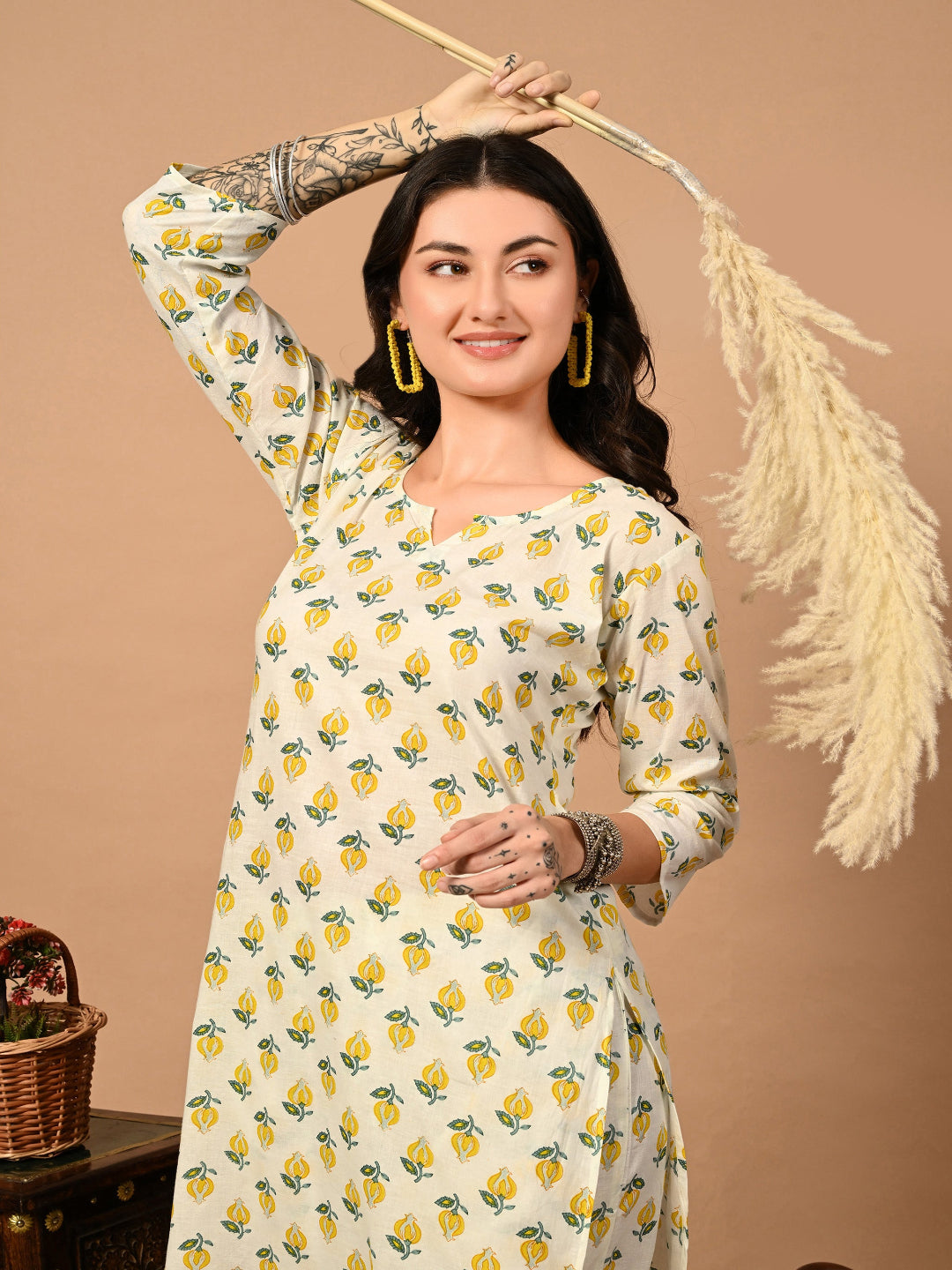 Woman wearing a white dress with yellow floral patterns against a beige background
